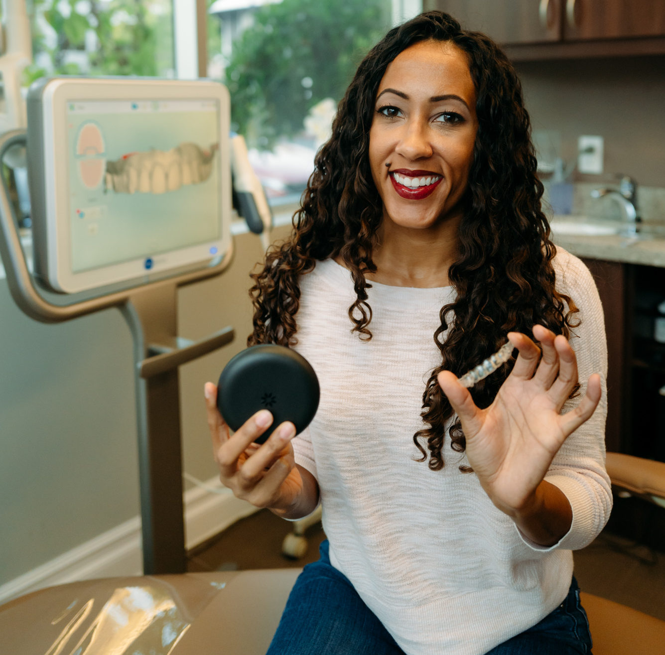Patient holding Invisalign aligners in front of 3D digital scanner